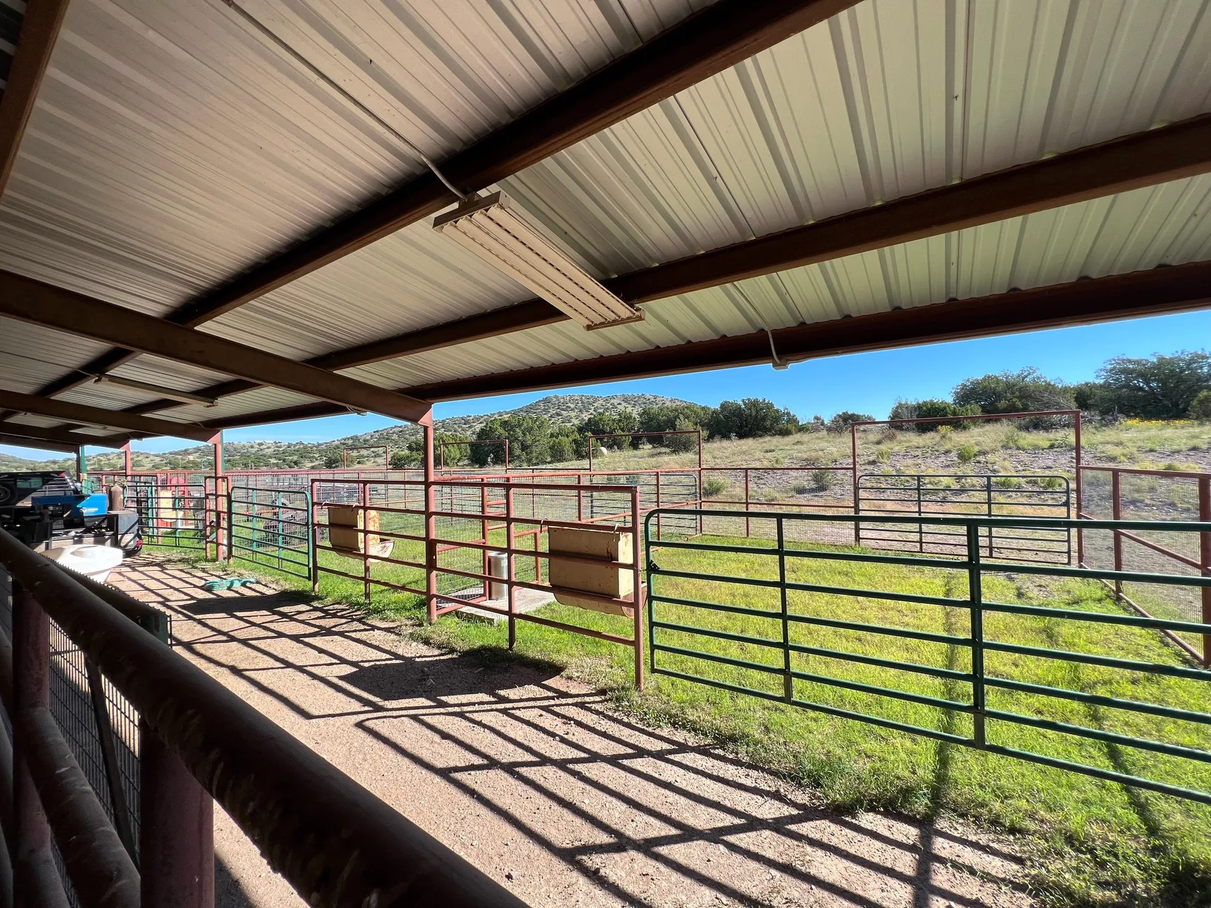 Covered outdoor pens with feeders looking to the hills