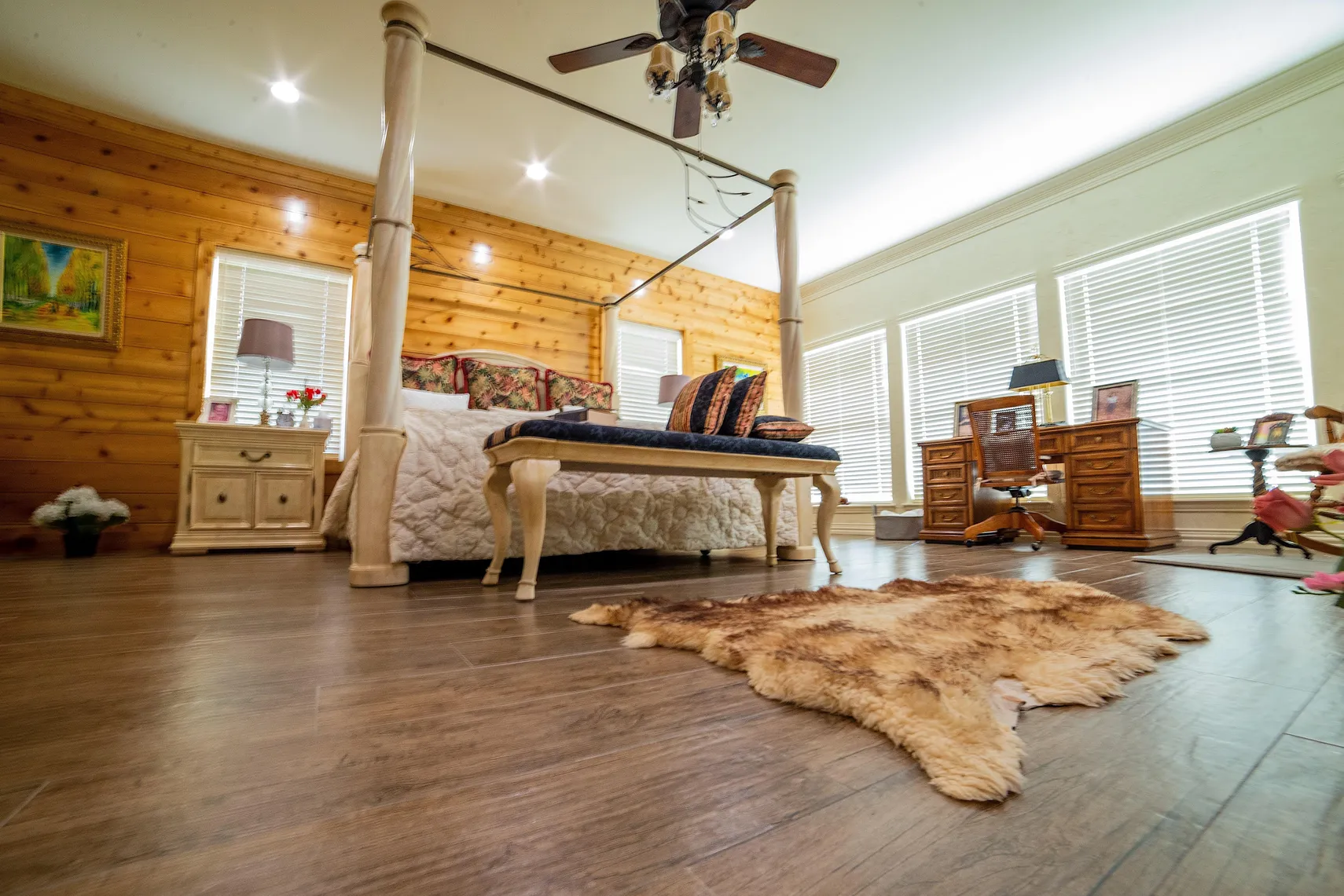 Primary suite with canopy bed and hardwood floors